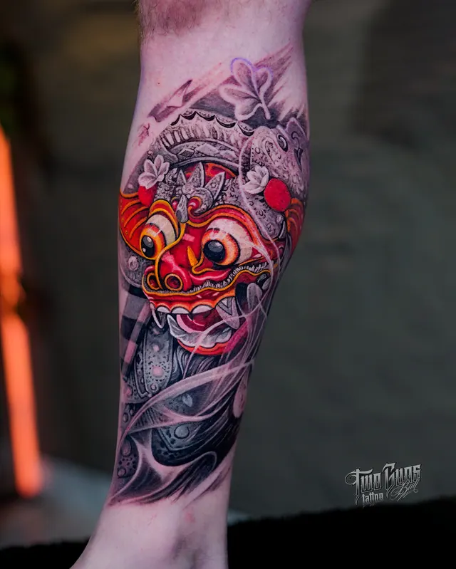 Red and grey Balinese Barong mask lower leg tattoo with poleng cloth and frangipani, freshly tattooed