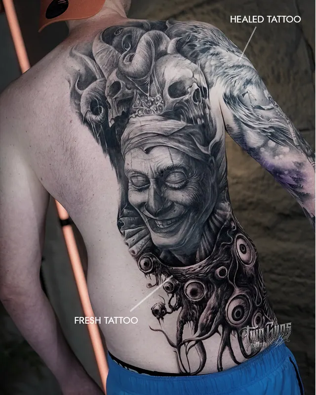 Black and grey back tattoo of a jester with skulls, shown healed and fresh