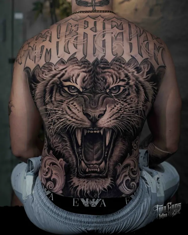 Black and grey realism full back tattoo of a roaring tiger with blackletter lettering