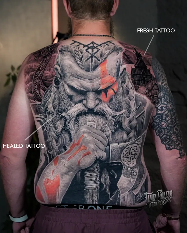 Full back tattoo of a bearded god figure with orange accents, shown fresh and healed