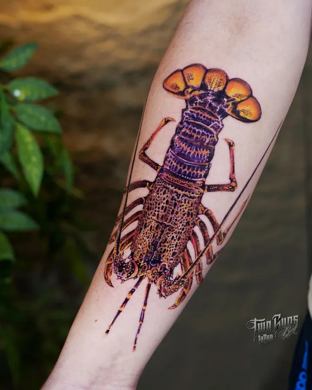 Colour forearm tattoo of a spiny lobster in orange and purple