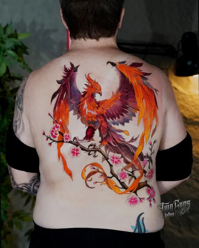 Colour upper back tattoo of a phoenix on a cherry blossom branch in orange and red
