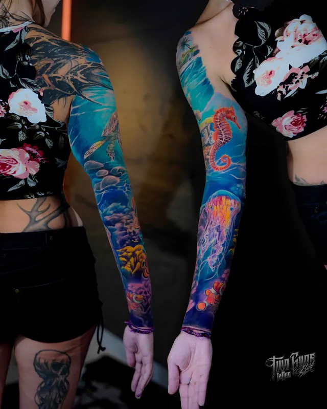 Colour full sleeve tattoo of sea life and flowers in blues and teals on a woman's arm, two angles