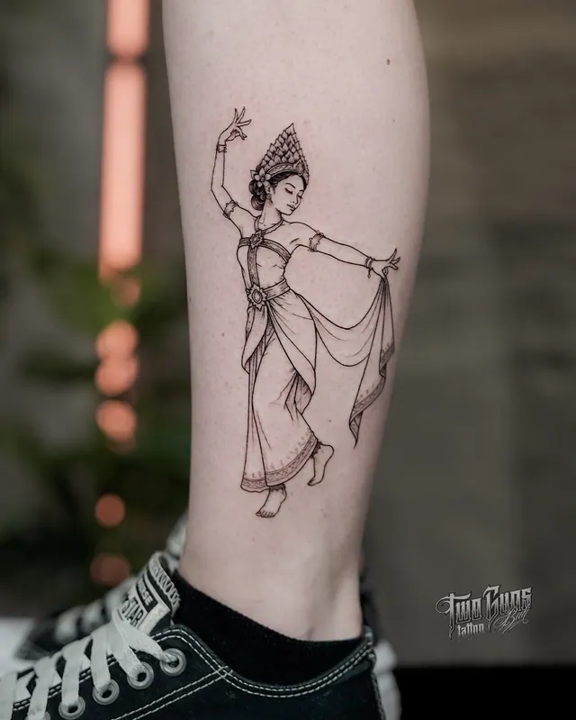 Fine line calf tattoo of a Balinese dancer in a traditional gelungan headdress