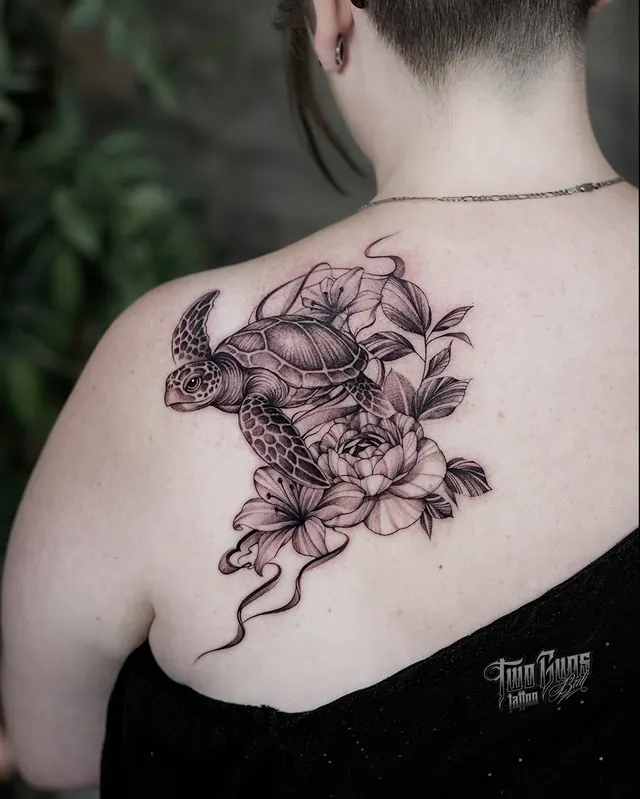 Fine line sea turtle tattoo with peonies and lilies on a woman's shoulder blade