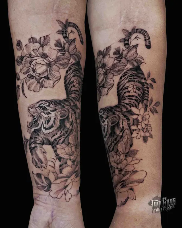 Fine line black and grey forearm sleeve tattoo of a tiger among magnolia flowers, shown from two angles