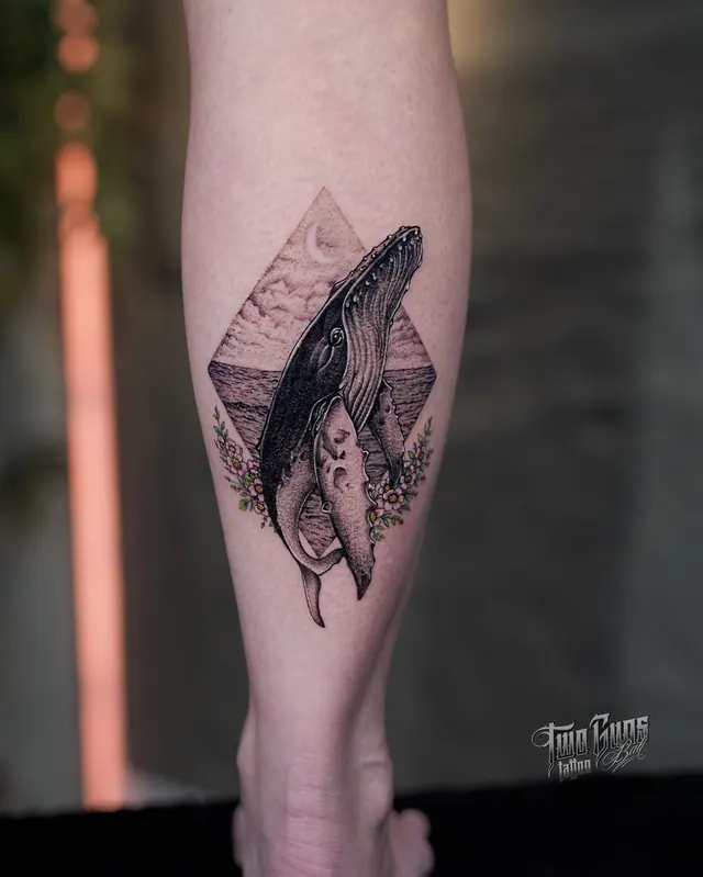 Fine line humpback whale calf tattoo in a diamond frame with mountains, a crescent moon and flowers
