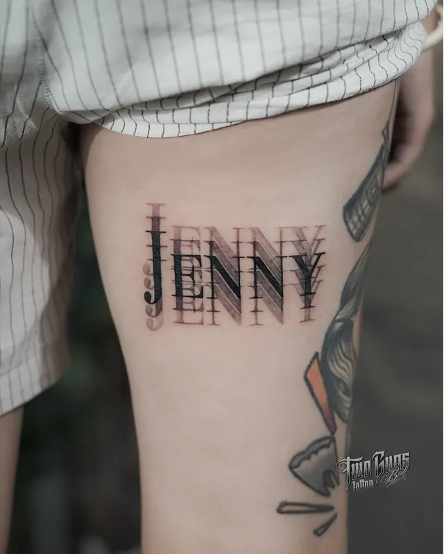 Blackletter name tattoo reading Jenny on the ribs, shaded for a three-dimensional look