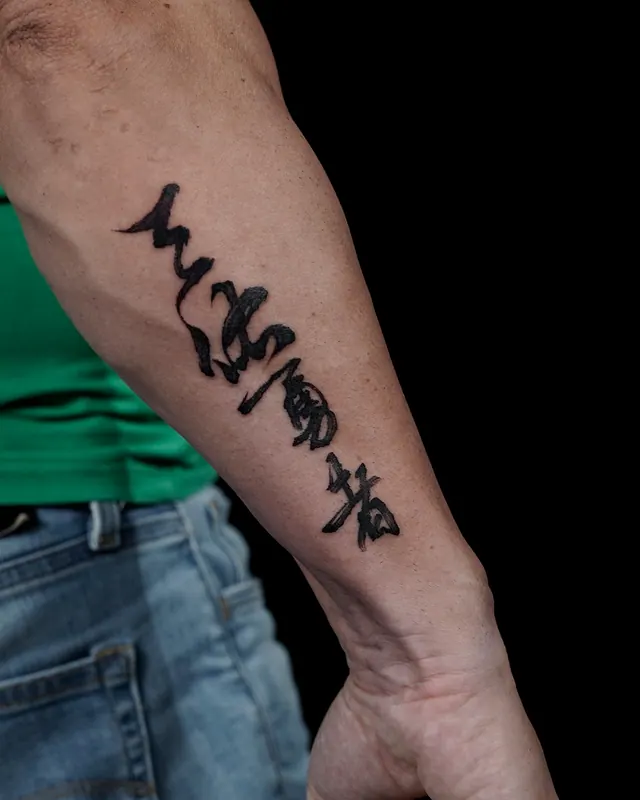 Japanese kanji forearm tattoo in bold brushed blackwork