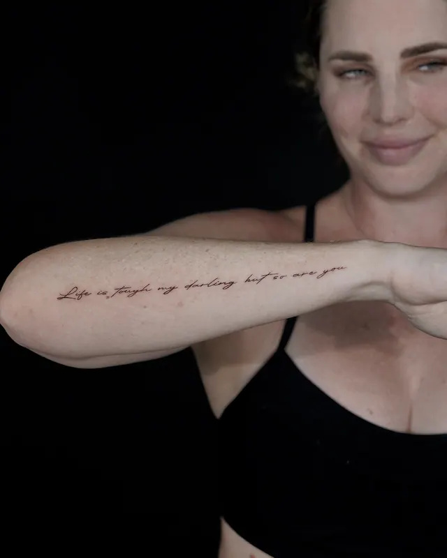 Fine line handwritten script tattoo along a woman's inner forearm
