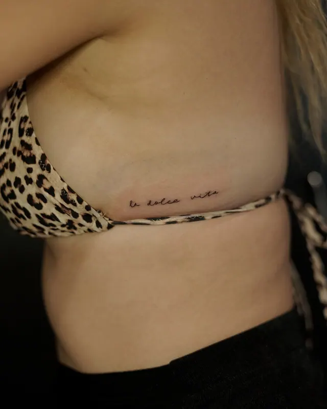 Fine line handwritten script tattoo along a woman's ribs