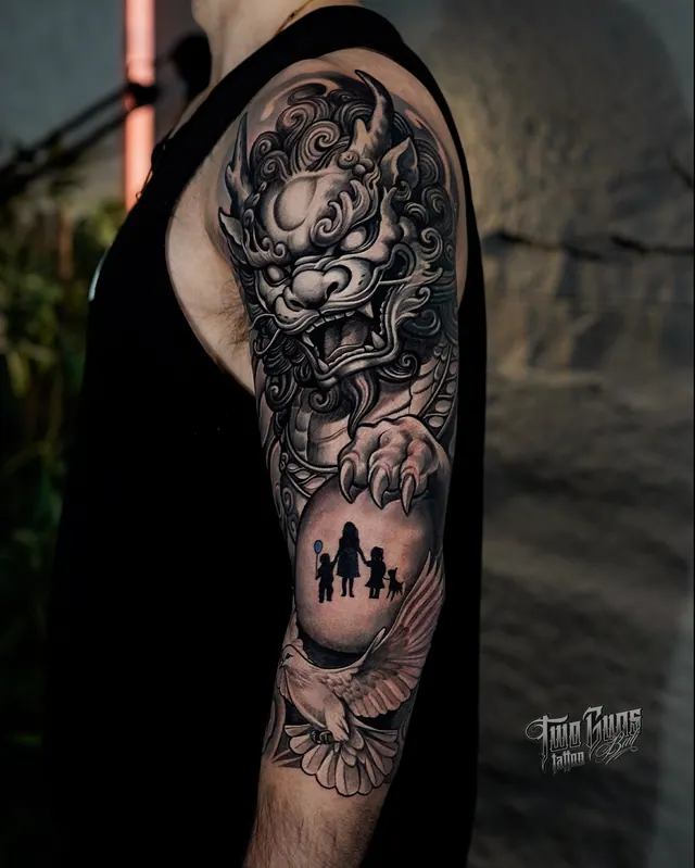 Black and grey Japanese upper arm tattoo of a lion dog with clouds and a family silhouette