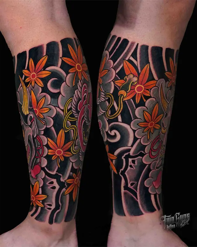 Traditional Japanese lower leg tattoos of chrysanthemums on a black wave background