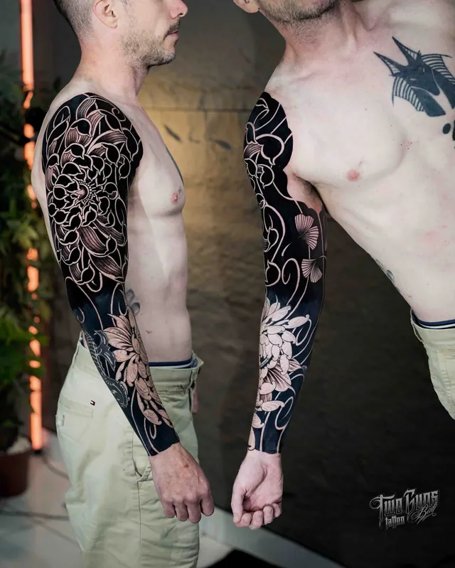 Blackwork full sleeve tattoos with negative space florals, shown on two clients