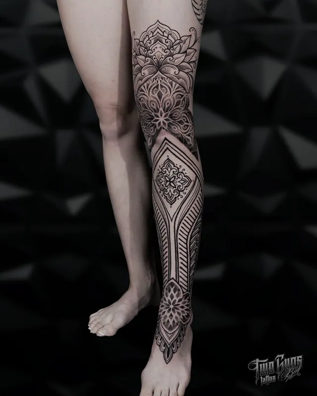 Fine line mandala and ornamental tattoo from knee to ankle on a woman's leg