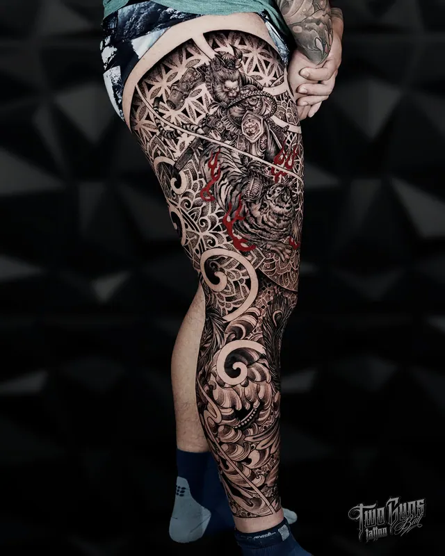 Ornamental geometric full leg sleeve tattoo with red accents