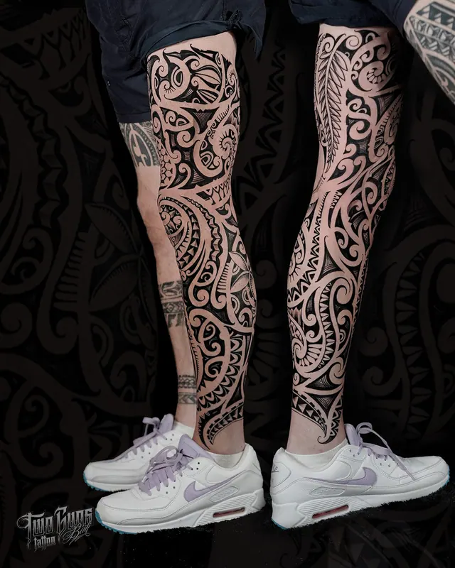 Maori style lower leg tattoos in black, shown on both legs
