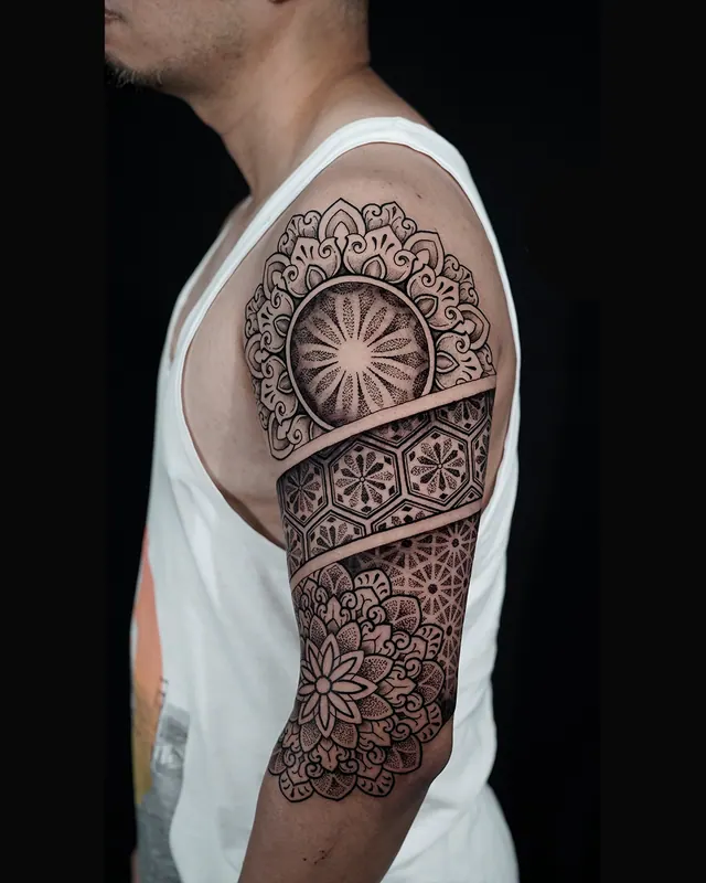 Dotwork mandala half sleeve tattoo with a sunburst centre on the upper arm