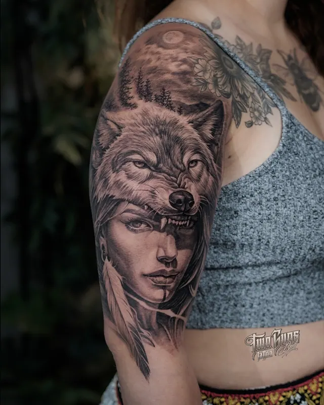 Black and grey realism upper arm tattoo of a woman wearing a wolf headdress