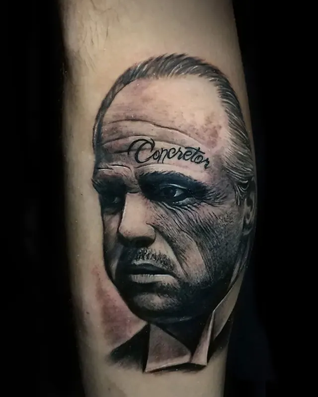 Black and grey realism calf tattoo portrait of the Godfather with Corleone lettering