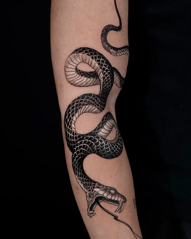 Black and grey realistic snake tattoo coiled around the forearm