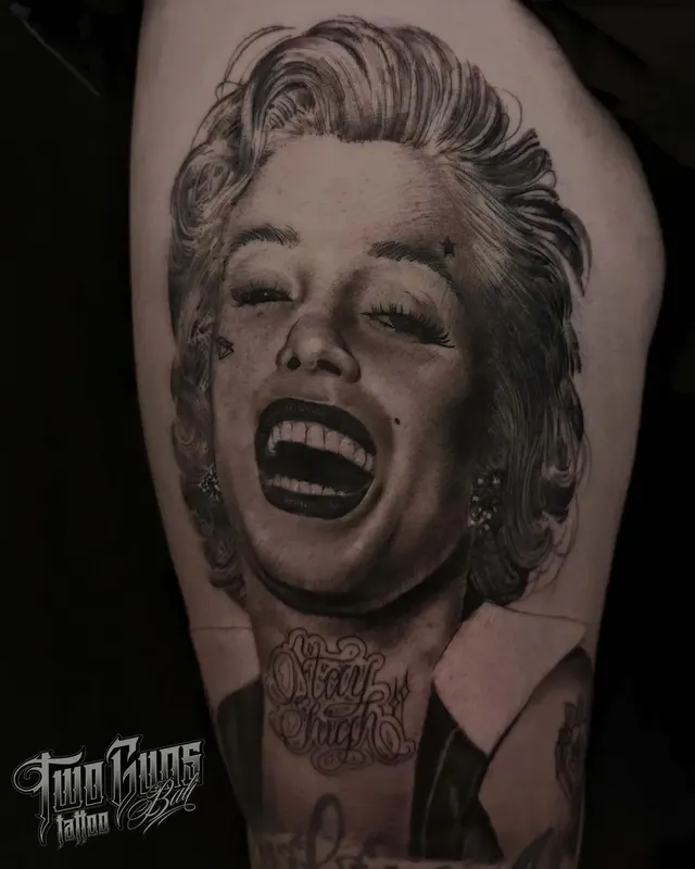 Black and grey realism thigh tattoo portrait of Marilyn Monroe laughing