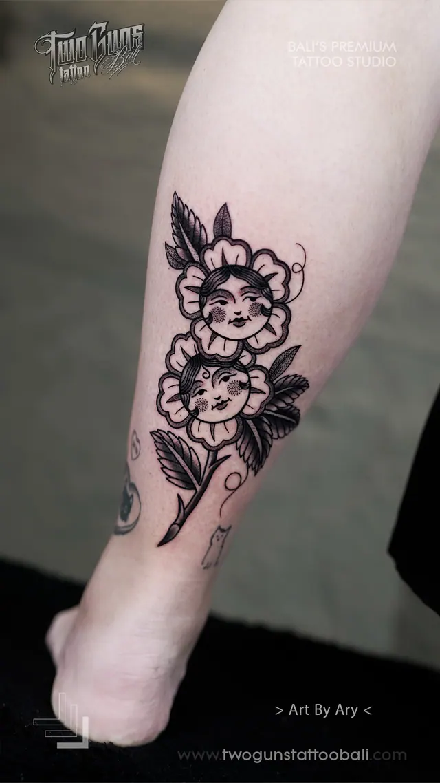 Fine line leg tattoo of flowers with women's faces, shown from another angle