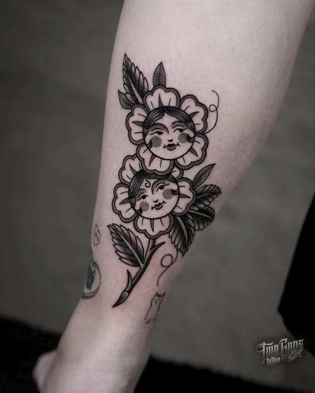 Fine line calf tattoo of flowers with women's faces in the blooms