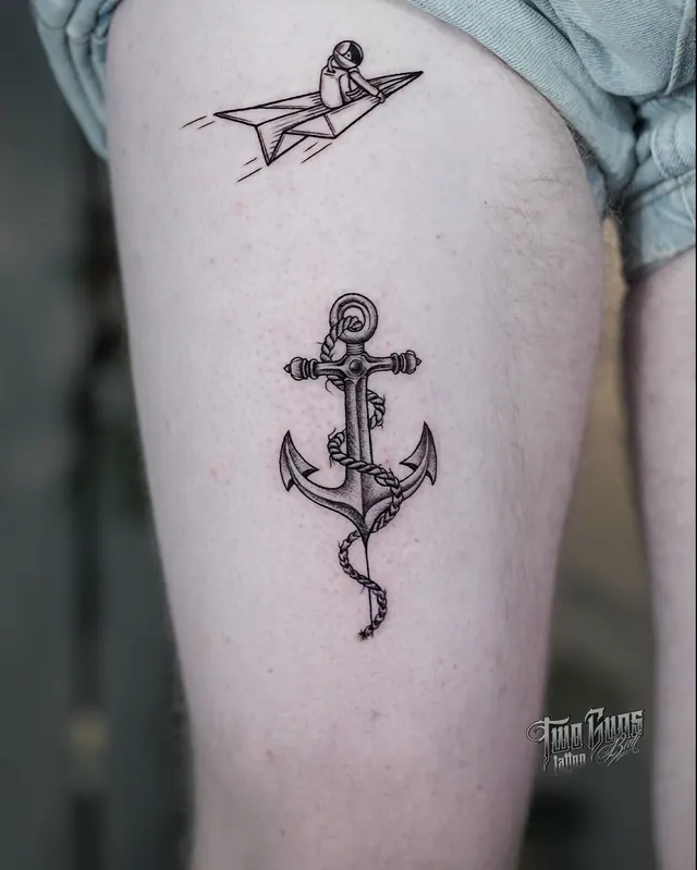 Fine line paper plane and anchor tattoos on the thigh