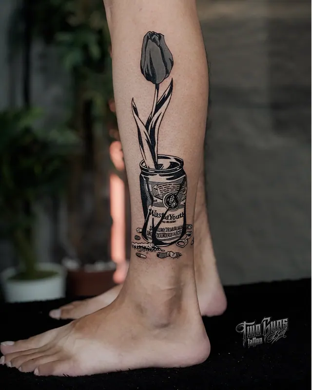 Small black and grey tattoo of a tulip in a tin can, above the ankle