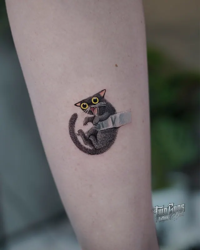 Small forearm tattoo of a black cat holding a knife