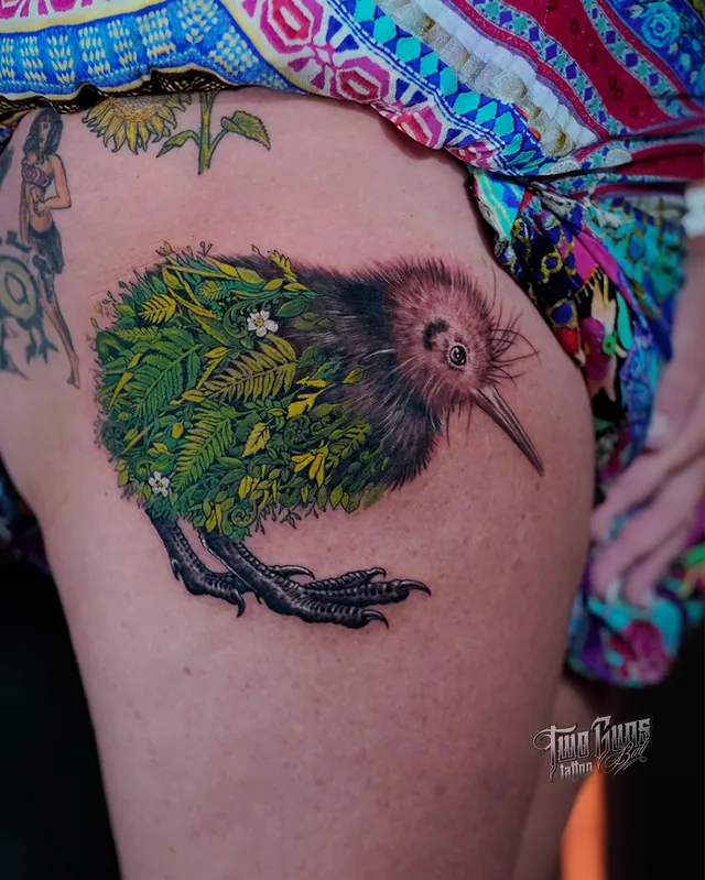 Colour thigh tattoo of a kiwi bird among ferns