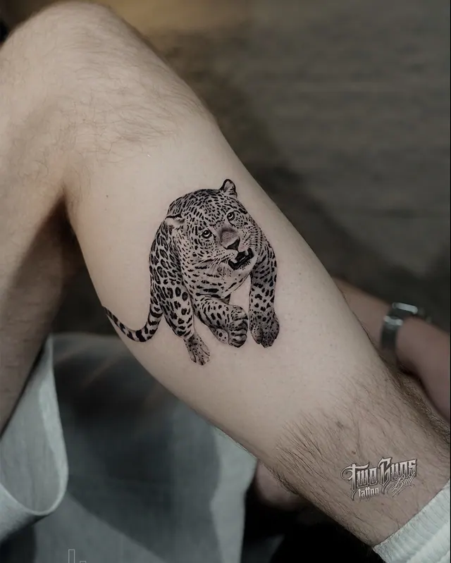 Fine line leopard tattoo crouching on the upper arm