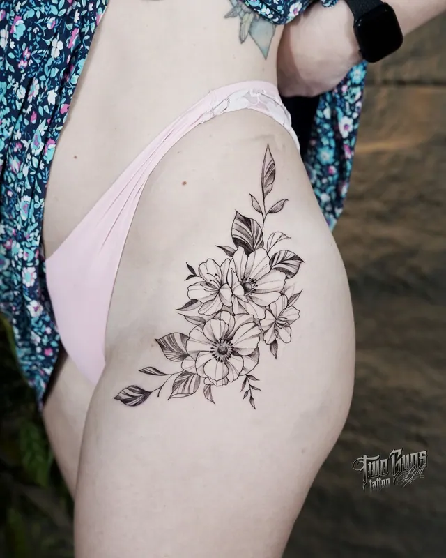 Delicate fine line flower tattoo on a woman's hip