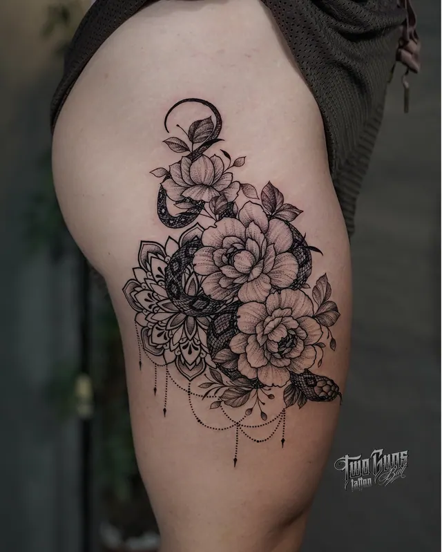 Fine line peony and moth hip tattoo with ornamental chain detail on a woman