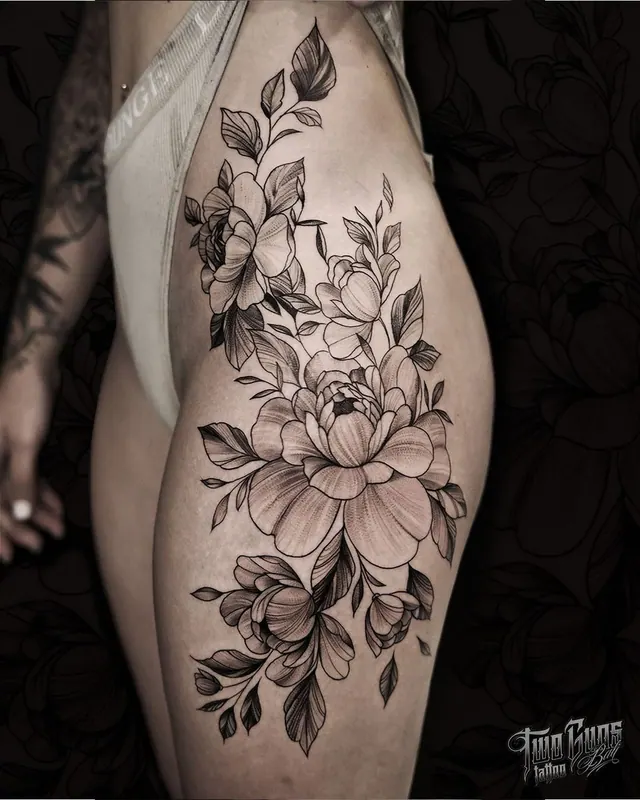 Fine line magnolia and peony thigh tattoo on a woman