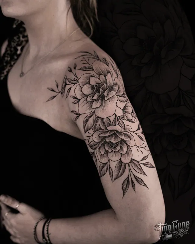 Fine line peony and botanical tattoo on a woman's shoulder and upper arm