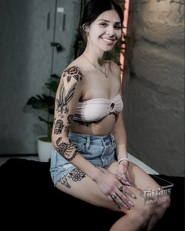 Blackwork traditional arm and leg tattoos on a woman, seated