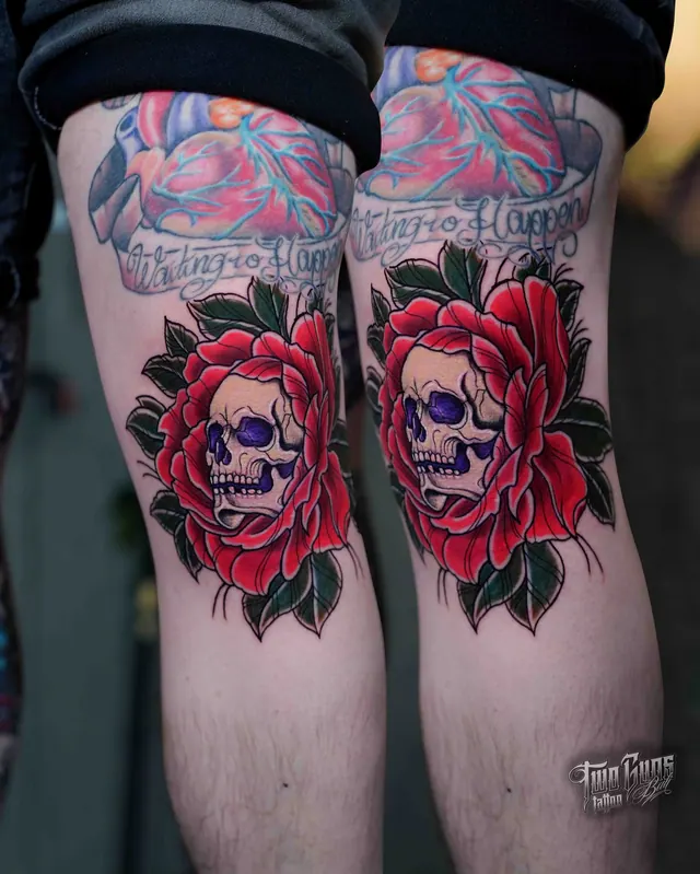 Matching colour tattoos of a sugar skull in a red rose on each knee