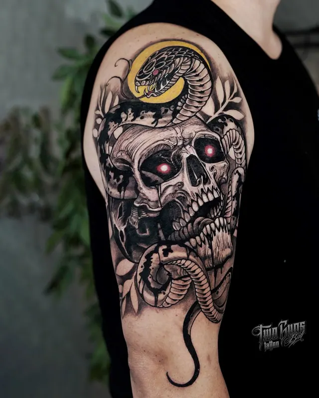 Upper arm tattoo of a skull with a snake and a gold crescent moon