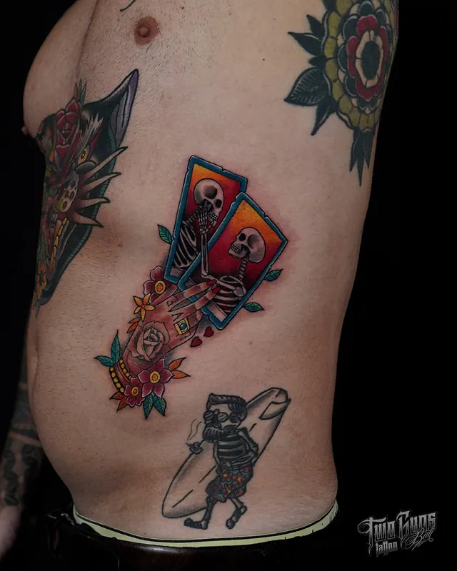 Colour traditional rib tattoos of playing cards, a skull, a dagger and a skeleton