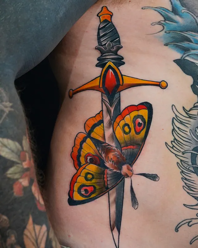 Colour traditional rib tattoo of a moth on a dagger