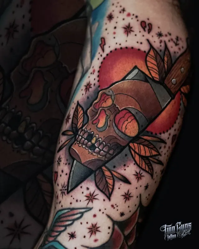 Colour traditional upper arm tattoo of a skull with a dagger and banner